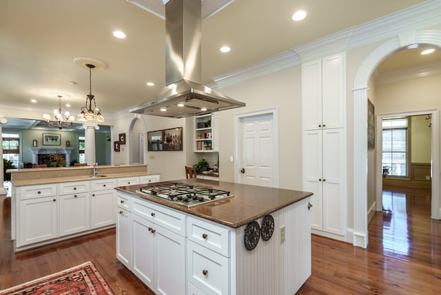 kitchen with white cabinetry, stainless steel gas cooktop, island range hood, a kitchen island, and ornamental molding