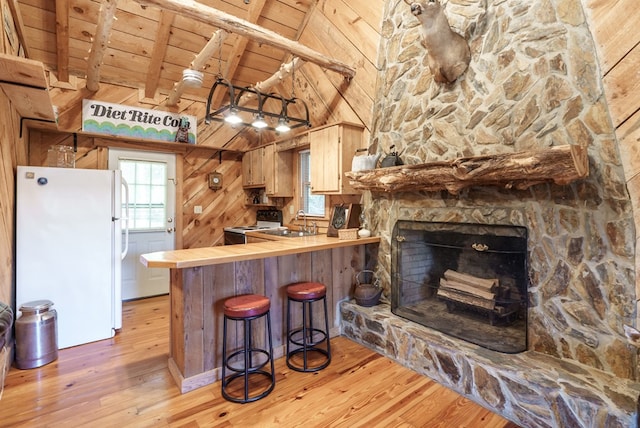 kitchen featuring wooden ceiling, beamed ceiling, white refrigerator, wood walls, and light hardwood / wood-style floors