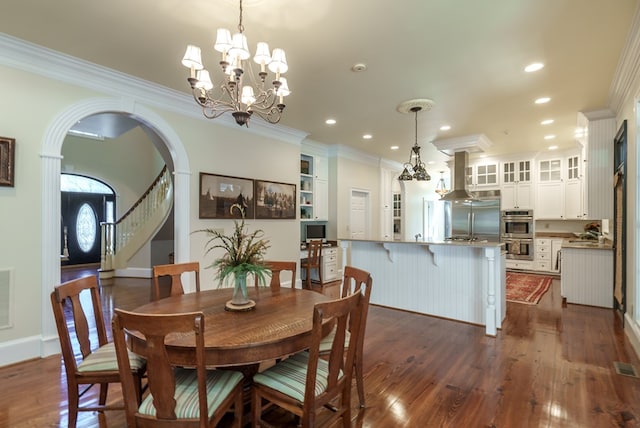 dining area with dark hardwood / wood-style floors, crown molding, and a notable chandelier