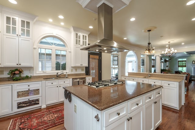 kitchen with island exhaust hood, stainless steel appliances, sink, pendant lighting, and a kitchen island