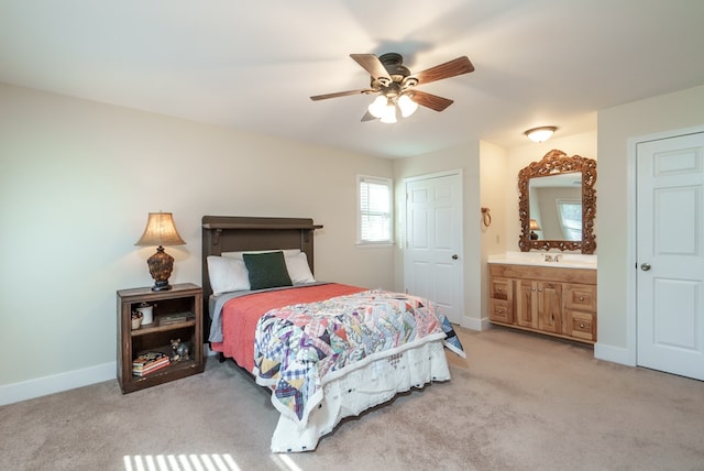 bedroom featuring light carpet, ensuite bath, and ceiling fan