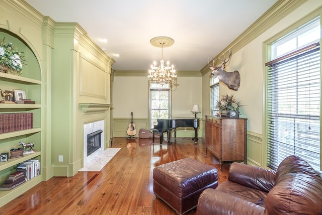 living room featuring a fireplace, built in shelves, a healthy amount of sunlight, and a notable chandelier