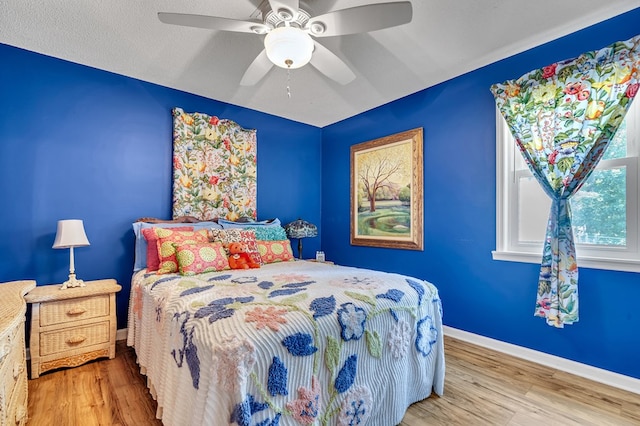 bedroom featuring ceiling fan, hardwood / wood-style floors, and a textured ceiling