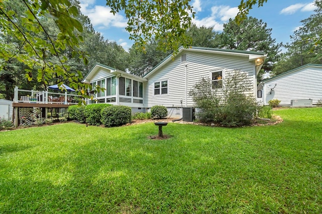 rear view of house with a sunroom, a deck, and a yard