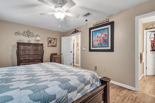 bedroom with ceiling fan, light wood-type flooring, and a textured ceiling