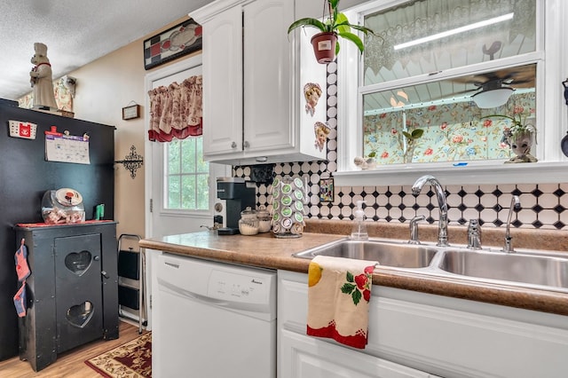 kitchen featuring white cabinets, dishwasher, sink, and a textured ceiling