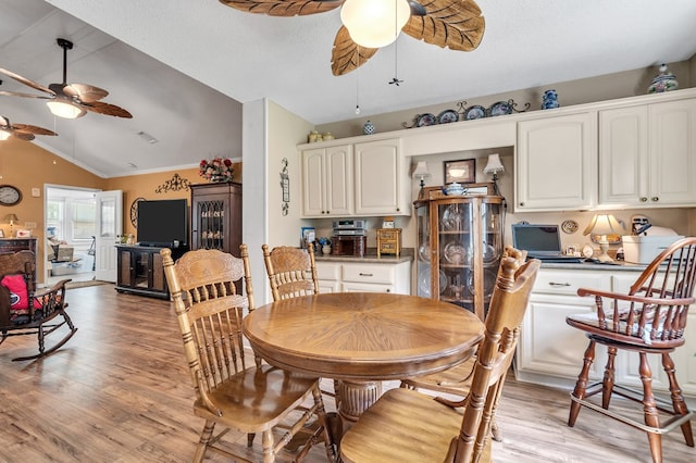 dining area with light wood-type flooring, a textured ceiling, ceiling fan, crown molding, and lofted ceiling