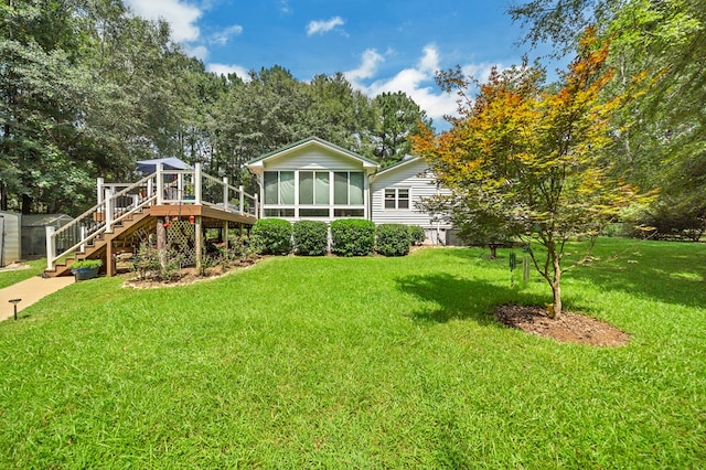 rear view of house with a yard, a deck, and a sunroom