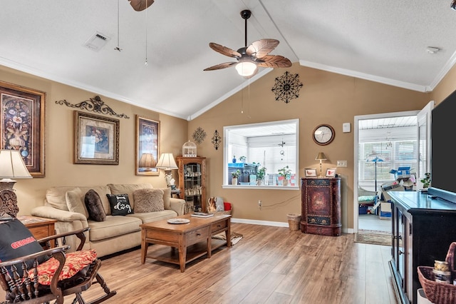 living room with ceiling fan, light hardwood / wood-style flooring, a textured ceiling, vaulted ceiling, and ornamental molding