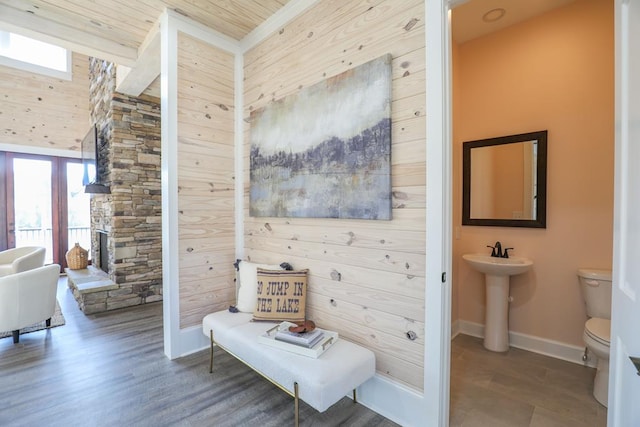 bathroom featuring toilet, wooden walls, baseboards, and wood finished floors