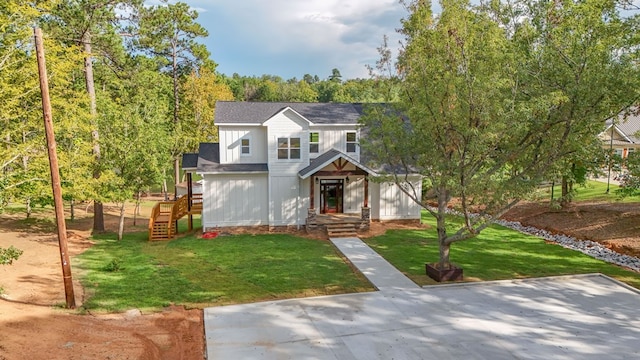 view of front facade featuring roof with shingles, board and batten siding, and a front yard