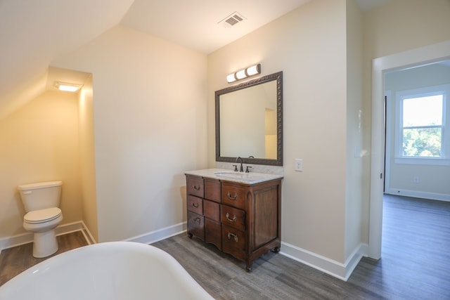 bathroom with a freestanding tub, visible vents, vanity, and wood finished floors