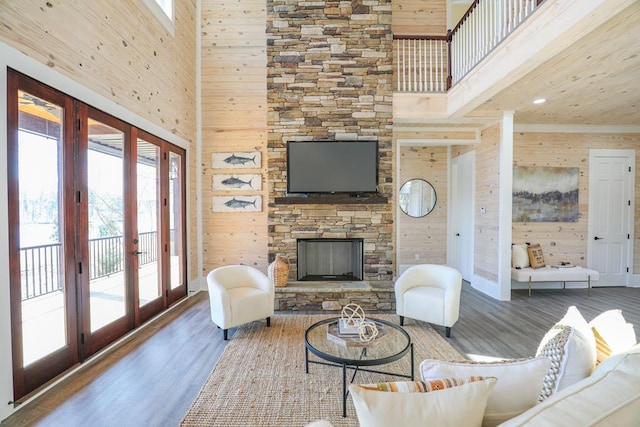 living room featuring french doors, wood walls, a fireplace, and wood finished floors