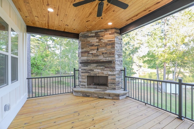 wooden terrace featuring an outdoor stone fireplace and a ceiling fan