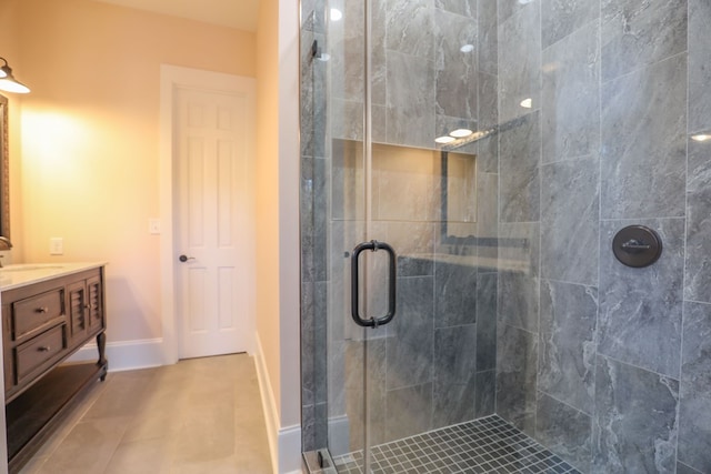 bathroom featuring tile patterned flooring, baseboards, a shower stall, and vanity