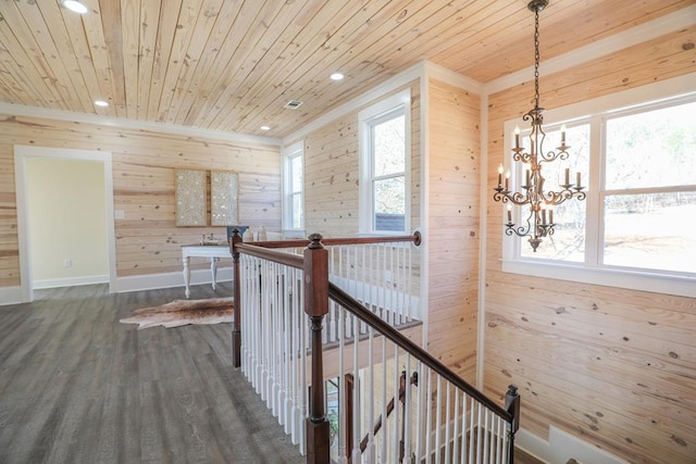 corridor with a wealth of natural light, dark wood-style flooring, wooden ceiling, and an upstairs landing