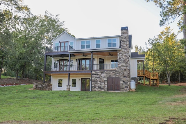 rear view of property featuring a lawn, a chimney, a balcony, and a ceiling fan