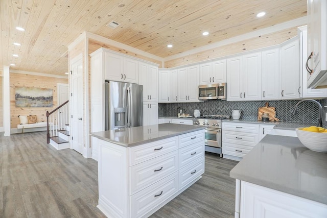 kitchen featuring wooden ceiling, wood finished floors, a sink, appliances with stainless steel finishes, and a center island