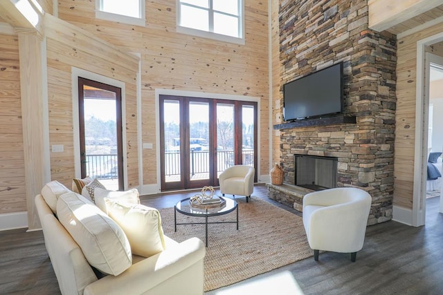 living area with a fireplace, a high ceiling, wood walls, wood finished floors, and baseboards