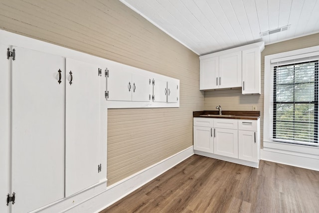 kitchen with dark wood-type flooring, wooden ceiling, sink, and white cabinets