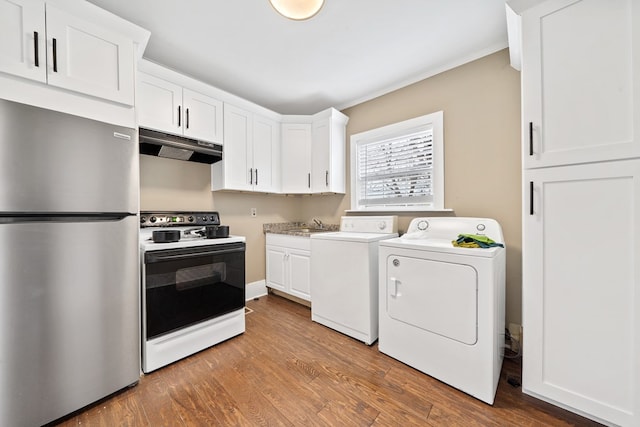 clothes washing area with hardwood / wood-style flooring, crown molding, sink, and washer and clothes dryer