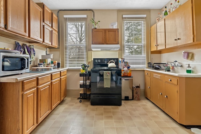 kitchen with black electric range oven, a textured ceiling, and a wealth of natural light