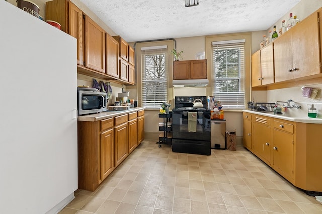 kitchen featuring black electric range, fridge, a textured ceiling, and white refrigerator