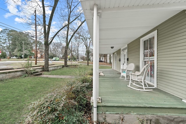 wooden terrace featuring a lawn and covered porch