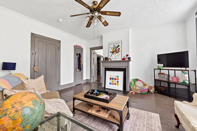 living room with dark hardwood / wood-style flooring, ceiling fan, ornamental molding, and a textured ceiling