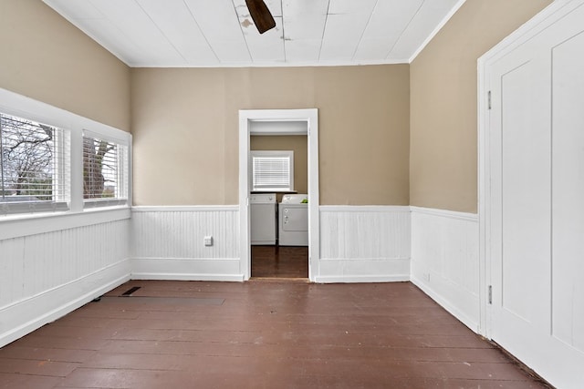 empty room with dark wood-type flooring, independent washer and dryer, and crown molding