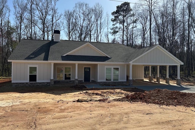 view of front of house featuring roof with shingles, board and batten siding, and a chimney