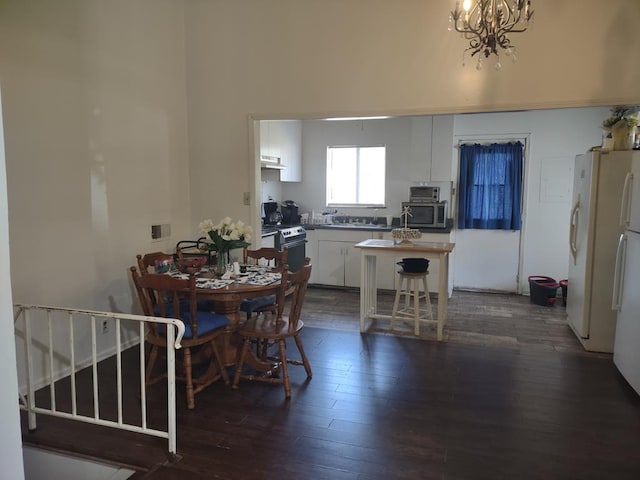 dining area with dark wood-style floors, stairs, and a notable chandelier