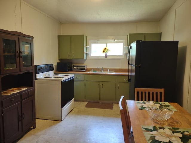 144 Bell Ave, Milledgeville, GA 31061 - kitchen with white electric stove, green cabinetry, freestanding refrigerator, a sink, and light flooring