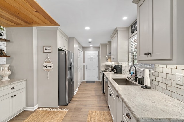 kitchen featuring tasteful backsplash, sink, white cabinetry, stainless steel appliances, and light stone counters