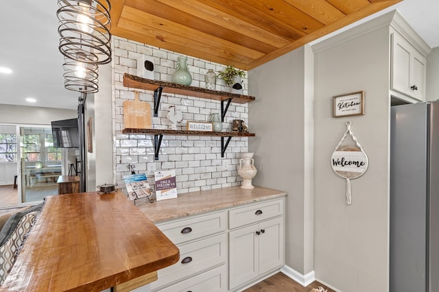 bar featuring wooden counters, pendant lighting, white cabinets, stainless steel fridge, and wooden ceiling