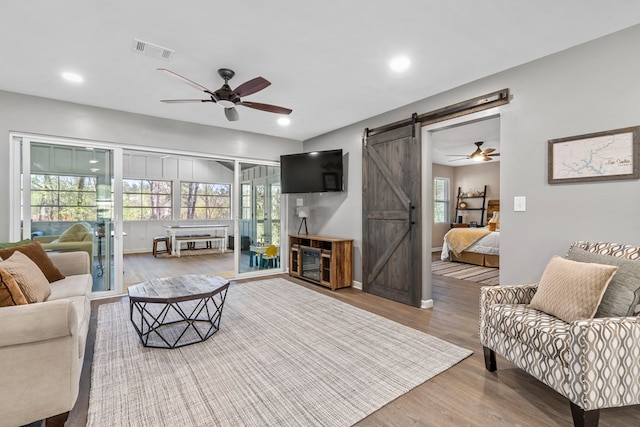 living room with ceiling fan, hardwood / wood-style floors, and a barn door