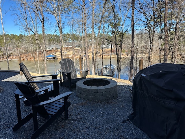 view of yard featuring a water view, an outdoor fire pit, and a dock