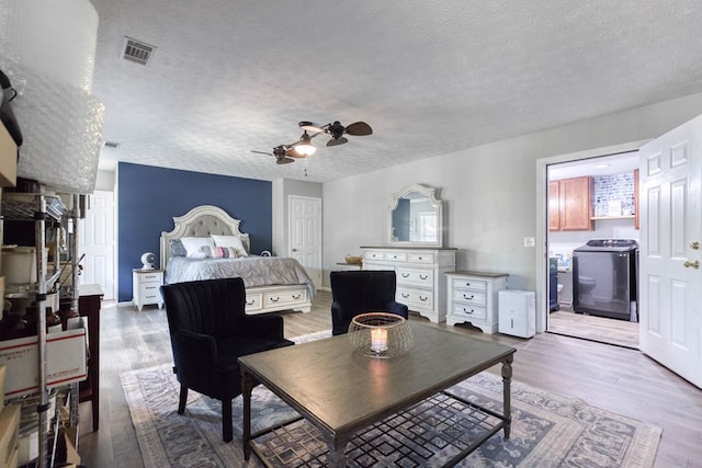 bedroom with visible vents, ceiling fan, washer / clothes dryer, wood finished floors, and a textured ceiling