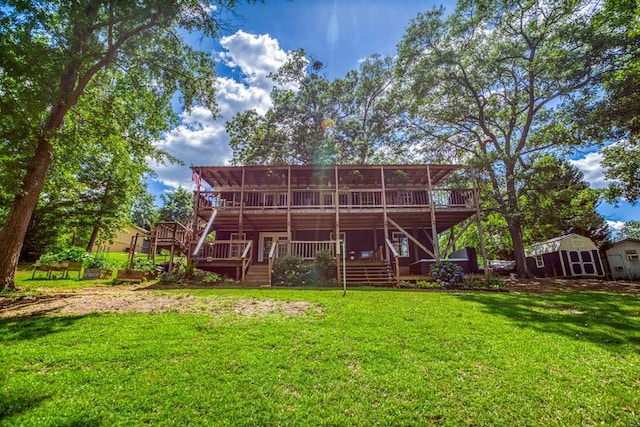 back of house featuring stairway, a deck, and a yard