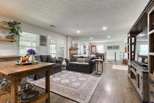 living room featuring a textured ceiling, recessed lighting, dark wood-style flooring, a fireplace, and visible vents