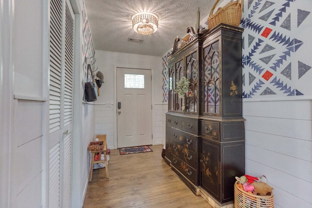 foyer featuring a textured ceiling, visible vents, and light wood-style floors