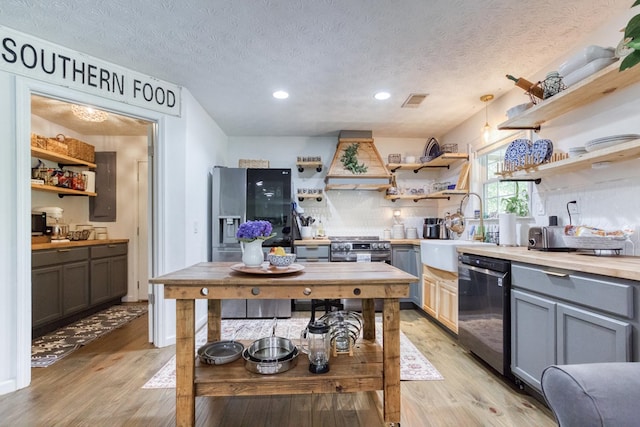 kitchen with light wood-style flooring, a sink, dishwasher, open shelves, and custom range hood