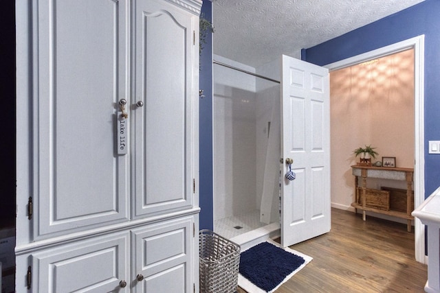 full bathroom featuring a textured ceiling, a stall shower, and wood finished floors