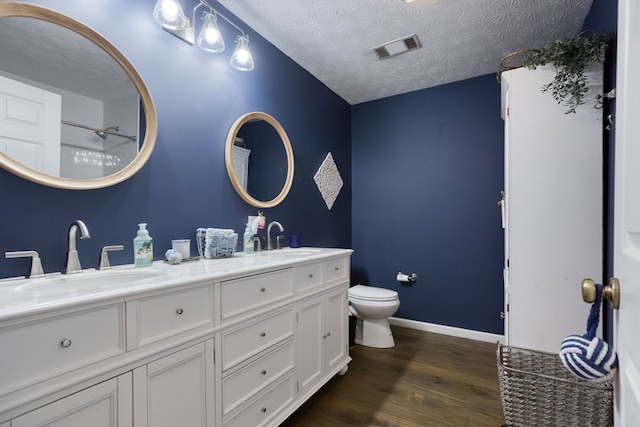 bathroom featuring a textured ceiling, visible vents, a sink, and wood finished floors