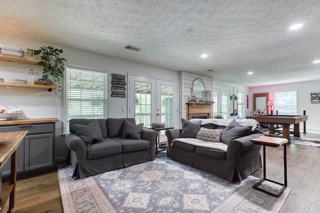 living room featuring plenty of natural light, visible vents, wood finished floors, and french doors