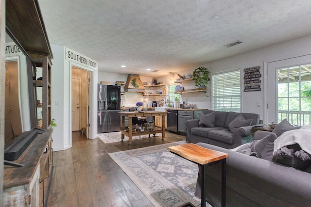 living area featuring a textured ceiling, visible vents, dark wood-type flooring, and recessed lighting