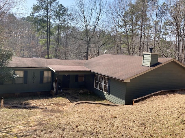 view of property exterior with roof with shingles and a chimney