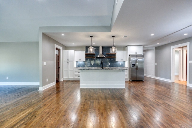 kitchen featuring tasteful backsplash, stainless steel refrigerator with ice dispenser, an island with sink, pendant lighting, and white cabinets