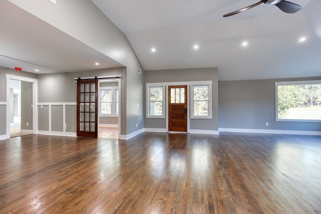 foyer entrance with a barn door, dark wood-type flooring, ceiling fan, and lofted ceiling