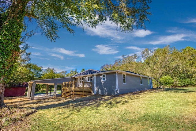 exterior space featuring a yard, a carport, and a wooden deck